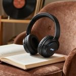 Cuffie bluetooth over-ear con ANC su libro e poltrona velluto