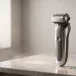 Rasoio elettrico moderno su un piano bagno con gocce d acqua