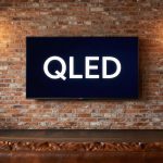 TV QLED salotto loft industrial con scritta QLED su schermo