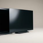 Due televisori affiancati a schermo spento su fondo neutro, confronto tra tecnologia OLED e QLED